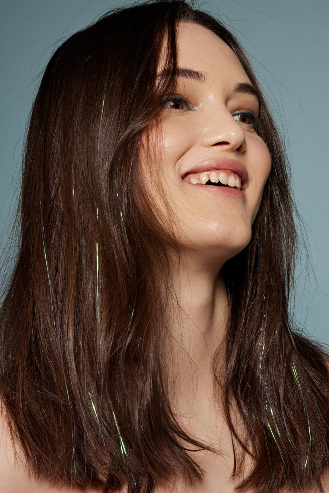 קלוז אפ על בחורה שבשיער שלה שזורים חוטי טינסל בצבעי לבן ירקרק - הנקראים אצלנו גווני פיות. מיועדים לחיבור עצמאי, פשוט וקבוע לשיער או לחיבור זמני - Shufizoo